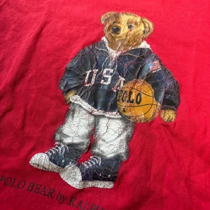 Röd t-shirt med Polo Bear från Ralph Lauren - Säljer en ruskigt fet polo bear t shirt. Den har ett litet hål på framsidan men inget man märker av när man har på den. Pris kan diskuteras.