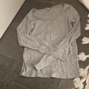 Grå långärmad topp med knappar - Säljer en ribbad grå långärmad tröja 