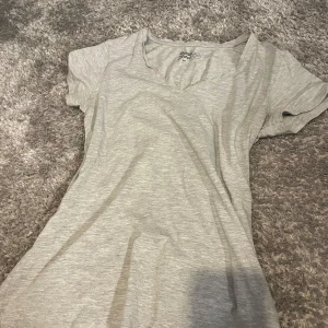 Ljusgrå t-shirt från Basic You - En enkel och mjuk ljusgrå t-shirt från Basic You i ekologisk bomull. T-shirten har korta ärmar och en v-ringad halsringning. Perfekt basplagg till garderoben. Andvänd fåtal gånger.