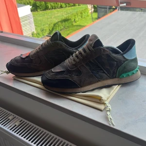 Valentino rockrunners stl 40-40,5 - Säljer ett par snygga sneakers från Valentino Garavani i mörkgrön och svart mocka med detaljer i skinn. Skorna är kamouflagefärgade, Perfekta för dig som vill sticka ut med stilrena och exklusiva sneakers. Hör av er om ytterligare bilder eller funderingar 