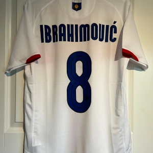Inter Milan bortatröja Ibrahimović 2007/08 - Säljer en vit Inter Milan bortatröja från säsongen 2007/08 med Ibrahimović och nummer 8 på ryggen. Tröjan har röd korsdesign på framsidan, broderat klubbmärke med jubileumsdetaljer och Pirelli.