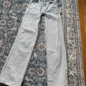 Ljusblå wide leg jeans - Säljer ett par ljusblå jeans med breda ben och klassisk femficksdesign. Jeansen har låg  midja , vida ben för en avslappnad och trendig look. Perfekta till sneakers eller boots. Säljer för att de är för små vid midjan.Man betalar frakten själv