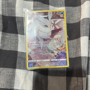 Frosmoth Pokémonkort - Samlarkort med Frosmoth, en is-inspirerad Pokémon. Kortet har färgstark design och visar Frosmoth i en glittrig miljö. Perfekt för dig som gillar Pokémon och vill utöka din samling med ett snyggt och unikt kort.