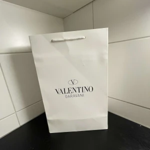 Valentino Garavani vita sneakers med marinblå detalj - Säljer ett par stilrena vita sneakers från Valentino Garavani med bred marinblå rem över vristen. Skorna har klassisk rund tå och platt sula, samt diskreta logodetaljer. Perfekta för dig som gillar exklusiva och trendiga sneakers.