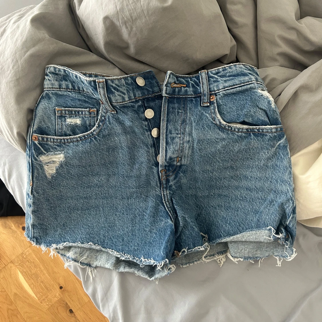 Blå jeansshorts med fransar och knappar