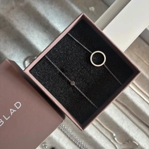 Silverfärgade armband från Edblad  - Två stilrena armband i silverfärg från Edblad. Det ena har en enkel cirkel som detalj och det andra ett litet runt hänge. Båda har tunn kedja och diskret design, perfekta för att kombinera eller bära var för sig.