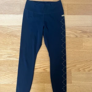 Nike träningstights  - Snygga och bekväma träningstights från Nike💕De är svarta med guld/gult färgat mönster längs med ena benet. Även loggan och texten är i samma färg som mönstret. Endast använda fåtal gånger och har inga defekter, loggan och allt tryckt är intakt (inget flagnat). Byxorna har tre olika fickor i midjan, ett av dem kan ses på bild 4. Det är alltså inte hål utan funktionella fickor, där man kan ha både mobil och annat under träningen. Nypris 1 149kr. Skriv gärna vid frågor eller funderingar☺️