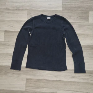 Svart långärmad tröja från Polarn O. Pyret - En enkel och stilren svart långärmad tröja från Polarn O. Pyret. Tröjan är ribbad och har rund halsringning. Perfekt basplagg med diskret logga på ärmen.