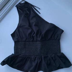 Svart oneshoulder topp med volang - Snygg svart oneshoulder topp med knytning vid axeln🥰kommer inte till användning och bara använt en gång! TRYCK INTE PÅ KÖP NU då jag säljer via Vinted me så skriv innan🫶🏻