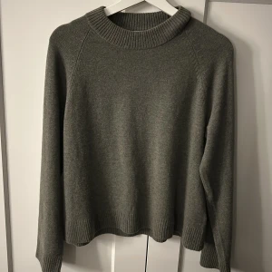 Grå grön stickad tröja  - Mysig grå stickad tröja från Wera med rund halsringning och ribbade muddar vid ärmslut och nederkant. Perfekt för kyligare dagar och enkel att matcha med olika outfits.