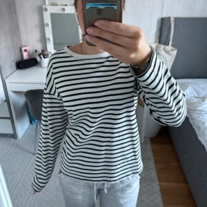 Randig långärmad tröja från Zara - Säljer en vit och svart randig långärmad tröja. Tröjan har en avslappnad passform och rund halsringning. Är en storlek M men passar S lika bra.