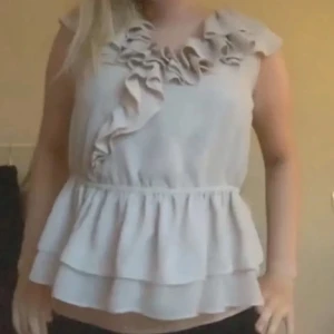  volangtopp - Säljer en beige/rosa ärmlös topp. Toppen har dubbla lager nertill och markerad midja för en luftig känsla. Perfekt för dig som gillar feminina detaljer och mjuka material. Har en liten defekt se bild, inget som syns när man bär toppen.