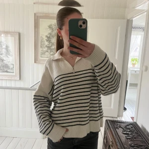 Vit och svart randig stickad tröja från MNG - Säljer en vit stickad tröja från Mango, MNG med svarta horisontella ränder. Tröjan har halv dragkedja framtill (i silver), krage och långa ärmar. Ribbstickade muddar och avslut. Använd men i fortfarande fint skick. På sista bilden visas en svag missfärgning längst ut på armen, men det går säkert att tvätta bort. Skriv gärna vid frågor☺️