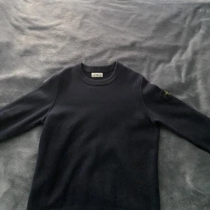 Svart stickad tröja från Stone Island - Säljer en mörkblå stickad tröja från Stone Island. Tröjan är i väldigt bra skick och har inga slitningar eller hål. Perfekt för kyligare dagar och enkel att matcha. 