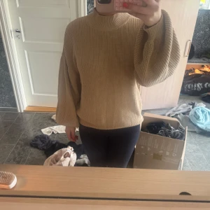 Beige stickad tröja med vida ärmar - Säljer en beige stickad tröja med rund hals och vida, långa ärmar. Tröjan har en avslappnad passform och är perfekt för kyligare dagar. Enkel och stilren design som passar till mycket.