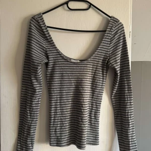 Grå och svart randig långärmad topp från Monki - Säljer en långärmad, tight topp från Monki i grått med svarta ränder. Djup rundad urringning och smal passform. Andvänd en gång💕