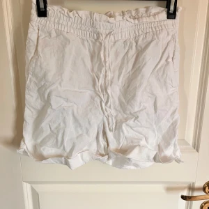 Vita shorts med resårmidja från C - Säljer ett par vita shorts från C i storlek XS. De har en bekväm resår i midjan och är tillverkade i ett lätt och luftigt tyg, perfekta för varma dagar. Passar dig som gillar en enkel och stilren look.