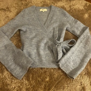 Ljusblå omlottkofta från Gina Tricot - Superfin ljusblå stickad omlottkofta från Gina Tricot i ullblandning. Koftan har långa ärmar, knyt i sidan och ribbade muddar. Storlek xs men passar även S.