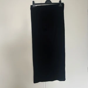 Svart långkjol från Zara - Säljer en svart långkjol från Zara. Kjolen har en rak och enkel design som gör den lätt att matcha med olika toppar. Perfekt för dig som gillar stilrena plagg och vill ha något som funkar året runt.