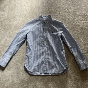 Blåvit randig skjorta från Polo Ralph Lauren - Polo Ralph lauren skjorta till säljes! Inga defekter, bra pris! Skjortan är köpt från kidsbrandstore och passar alla personer mellan 160-170 cm! Anledning till sälja är för att den är för liten för mig. Hör av er om minsta fundering!💫