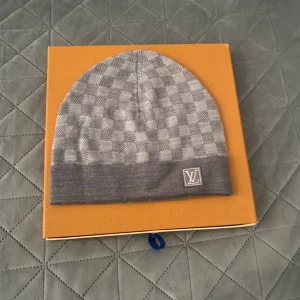 Grå rutig mössa  - Snygg grå mössa från med diskret rutigt mönster . Perfekt accessoar för att hålla värmen och samtidigt se stilren ut.