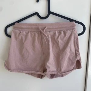 Ljusrosa shorts - Säljer ett par ljusrosa shorts från Warp med dragsko i midjan. De har en mjuk och bekväm passform, perfekt för varma dagar. Shortsen är tillverkade i bomull och har en enkel design med diskreta sömmar eller så kan man använda de för ett par sköna shorts att gå i hemma.