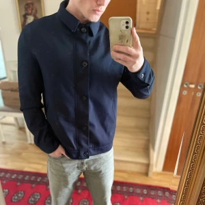 Mörkblå overshirt - Säljer en stilren mörkblå overshirt som är perfekt nu till sommaren.☀️Den har både knappar och dragkedja med en klassisk krage. Knappt använd och har ni frågor kan ni höra vav er!🙏