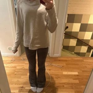 Beige stickad tröja med rund hals - Mysig beige stickad tröja med rund hals och långa ärmar. Tröjan har ribbade muddar vid ärmslut och nederkant. Perfekt för lager-på-lager under kyliga dagar. Har ett hål på ena armen se bild 3 