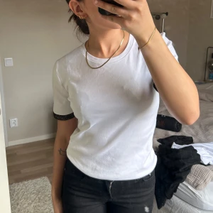 Vit t-shirt med glittrig kant - Säljer en vit t-shirt med korta ärmar och glittrig svart kant längst ner på ärmarna från Zara. Helt nytt, dock ingen prislapp kvar. Storlek M men är mer som XS/S