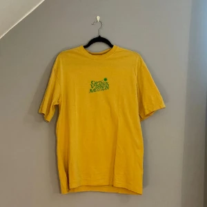 Oanvänd hm tröja med tryck  - Säljer en gul t-shirt med tryck i grönt både fram och bak. T-shirten har aldrig varit använd.