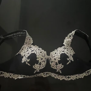 Mörkblå intimisimi bh - Supersnygg mörkblå bh med krämvit blommig spetsdetalj över kupor och axelband. Toppen har en feminin v-ringning och tunna axelband, perfekt för att ge outfiten en romantisk touch. Knappt andvänd!!💞