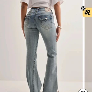 True Religion Joey Low Rise Flare Jeans - Snygga ljusblå jeans från True Religion, modell Joey Low Rise Flare. De har låg midja, utsvängda ben och klassiska bakfickor med lock och silverfärgade knappar. Jeansen är i denim med coola slitningar och detaljerad sömnad. Jeansen är i storlek 24. De är endast använda ett par gånger. Lappen är bortklippt men följer med i byxfickan. Tyvärr är jeansen för korta för mig (1,73 cm). 