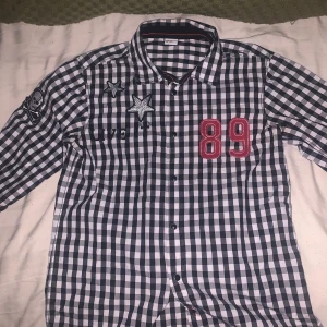 Emo tröja - Plad emo tröja med siffror och text på med patches. Själv thriftad med click knappar 