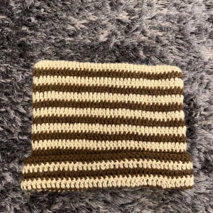 Randig virkad mössa i brunt och beige - Mössan har en rak form som ser ut som kattöron när den sätts på och är gjord i ett tjockare garn som känns både mjukt och varmt. Har aldrig använt, nyköpt. Alla priser kan diskuteras🤍