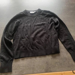 Svart prickig stickad tröja Kappahl - Svart stickad tröja från Kappahl i storlek M. Tröjan har diskreta prickar i samma färg över hela ytan och ribbade muddar vid hals, ärmslut och nederkant. Perfekt för dig som gillar enkel men ändå unik stil. Aldrig använd.