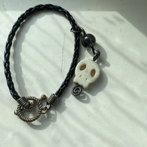 Svart flätat armband med dödskalle - Coolt svart flätat armband med en vit dödskalleberlock och en grå pärla💗Köpt på en marknad och endast testat💗 Pris går att diskutera!💗