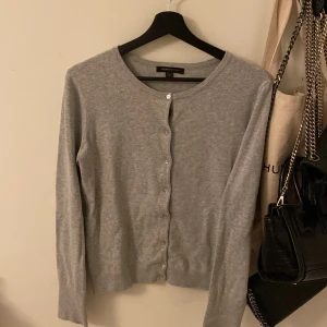 Grå kofta från Mywear Woman - En stilren grå kofta från Mywear Woman i storlek S. Koftan har rund halsringning, långa ärmar och knäppning framtill med små knappar. Perfekt att slänga över en t-shirt eller linne för en chill look.