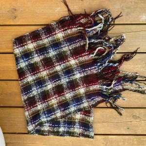 Rutig halsduk med fransar - Färgglad halsduk med fransar i ett rutigt mönster. Halsduken har färgerna röd, vit, blå, grön Mått: 156x41 cm ﻿100% akryl  Inga bilder när den sitter på mig! Katter finns i hemmet!