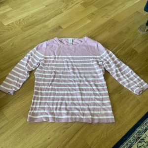 Randig lila tröja från Hillevi - Söt randig tröja från Hillevi i lila och vitt. Tröjan har trekvartsärm och är tillverkad i mjuk bomull 45% och viskos. Broderad krona nertill ger en extra detalj. Perfekt för dig som gillar en chill och stilren look.