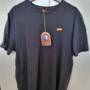 Marinblå iconic t-shirt från Parajumpers - Svart t-shirt från Parajumpers med klassisk passform. T-shirten har rund hals, korta ärmar och en gul detalj på bröstet samt ett broderat PJS-märke på ärmen. Tillverkad i mjuk bomull som känns skön mot huden.