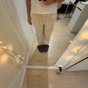 Beiga linnebyxor från ONLY med snörning - Säljer ett par beiga linnebyxor från ONLY med avslappnad passform och snörning i midjan. Byxorna är raka i modellen och har en bakficka. Perfekta för chill dagar eller när du vill ha en clean och enkel look.