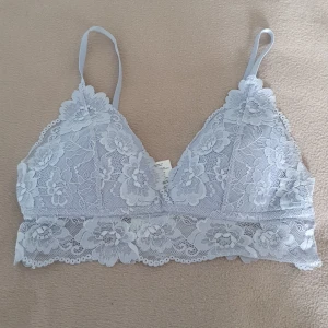 Ljusblå spets bralette från H&M - Supersöt ljusblå bralette från H&M i storlek 40. Topp i mjuk spets med blommigt mönster, justerbara axelband och bred spetskant nedtill. Perfekt för lager-på-lager eller som statement piece under en öppen skjorta. Pris kan diskuteras 