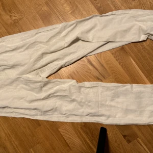 Vita linnebyxor Urban Classics - Snygga vita linnebyxor från Urban Classics med avslappnad passform och dragsko i midjan. Perfekta för varma dagar, med elastisk midja och raka ben. Lätta och luftiga, passar till chill eller cityhäng.