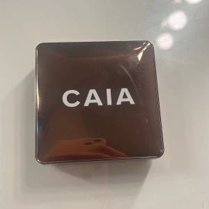 CAIA sminkpalett brun metallic - Snygg sminkpalett från CAIA i en stilren, fyrkantig brun metallic-förpackning med vit logga. Perfekt att ha i väskan för att snabbt fräscha upp sminket. Paletten har en lyxig känsla och är enkel att ta med sig.