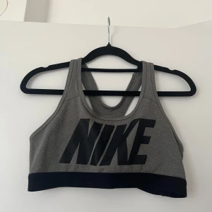 Grå sporttopp från Nike - Snygg grå sporttopp från Nike med stort svart logotryck framtill.