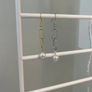 Asymmetriska örhäng med pärlor - Säljer ett örhängenmed kedjor i guld- och silverfärg, dekorerade med vita pärlor längst ner. Ena örhänget är i guld och det andra i silver. Perfekt för dig som gillar att sticka ut med accessoarerna. Hand gjorda om du trycken på köp nu köper du bara 1 örhänge inte två. Skriv vilken färg du vill ha eller om du vill ha båda💕1 för 10kr och båda för 15kr
