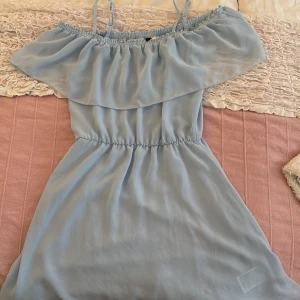 Ljusblå offshoulder klänning H&M Divided - Supersöt ljusblå kortklänning från H&M Divided med offshoulder och smala axelband. Klänningen har volang upptill och resår i midjan för en snygg passform. Tillverkad i ett lätt och luftigt polyestertyg, perfekt för varma dagar. Den är i storlek 34!!<3