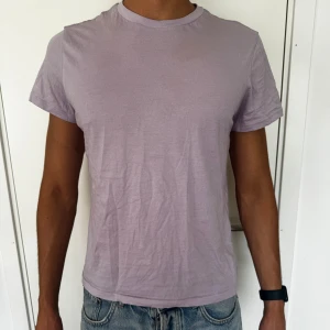 Ljuslila basic t-shirt - Enkel och stilren ljuslila t-shirt med rund hals och korta ärmar. T-shirten är i mjuk bomull och har en klassisk passform som funkar till jeans eller shorts. Perfekt för dig som gillar en clean och avslappnad look.