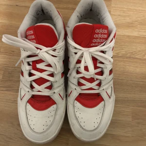 Adidas Originals Midcity Low - Snygga sneakers från Adidas i vitt och rött med klassiska tre ränder på sidan. Skorna har vit ovandel i syntet och mesh, röda detaljer på plös, tå och häl samt snörning framtill. Perfekta för dig som gillar retrostil och sportig vibe. Använda max 4 gånger annars i sig oskadda.