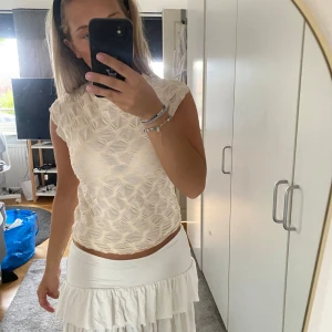 Vit mönstrad blus med struktur - Säljer en vit blus med coolt strukturerat mönster och lätt transparent känsla. Toppen är ärmlös och har en rund halsringning. Perfekt för dig som vill ha något unikt och trendigt i garderoben.